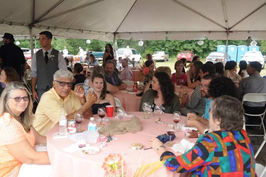 Wedding guests seated together at decorated tables beneath a reception tent