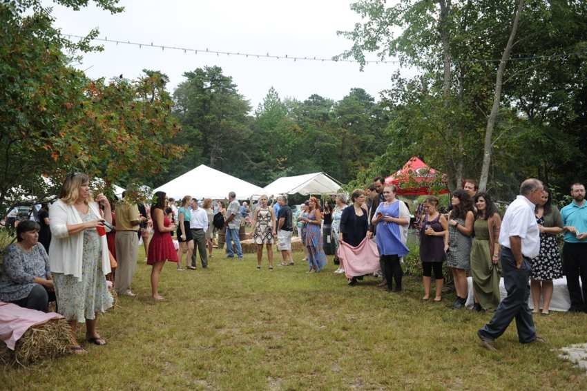 Wedding guests celebrating outside among trees and reception tents